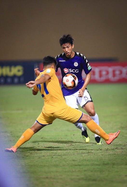 Đoàn Văn Hậu (5, Hà Nội FC) cố gắng đi bóng qua sự ngăn cản của cầu thủ Sông Lam Nghệ An. (Ảnh: Trọng Đạt/TTXVN)