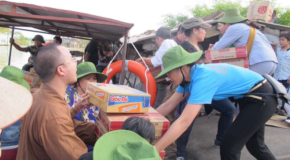 Trao các nhu yếu phẩm cần thiết như: Mỳ tôm, nước lọc, lương khô…tới người dân vùng lũ. (Ảnh: Thùy Dung/TTXVN​)