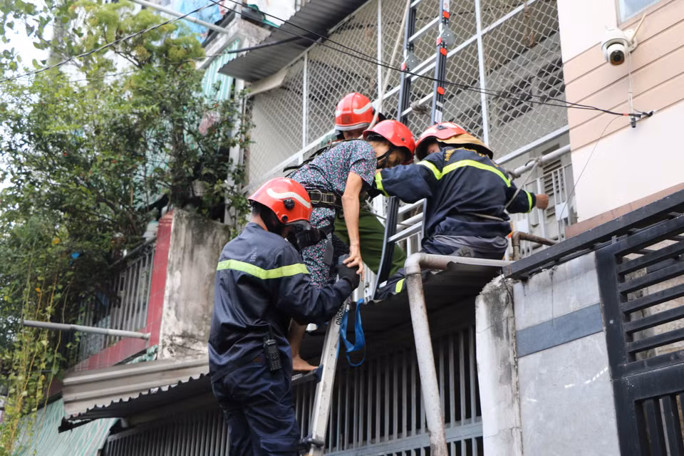 Lực lượng chức năng đưa hai nạn nhân ở trên gác bị mắc kẹt ra ngoài an toàn. (Ảnh: PV/Vietnam+)
