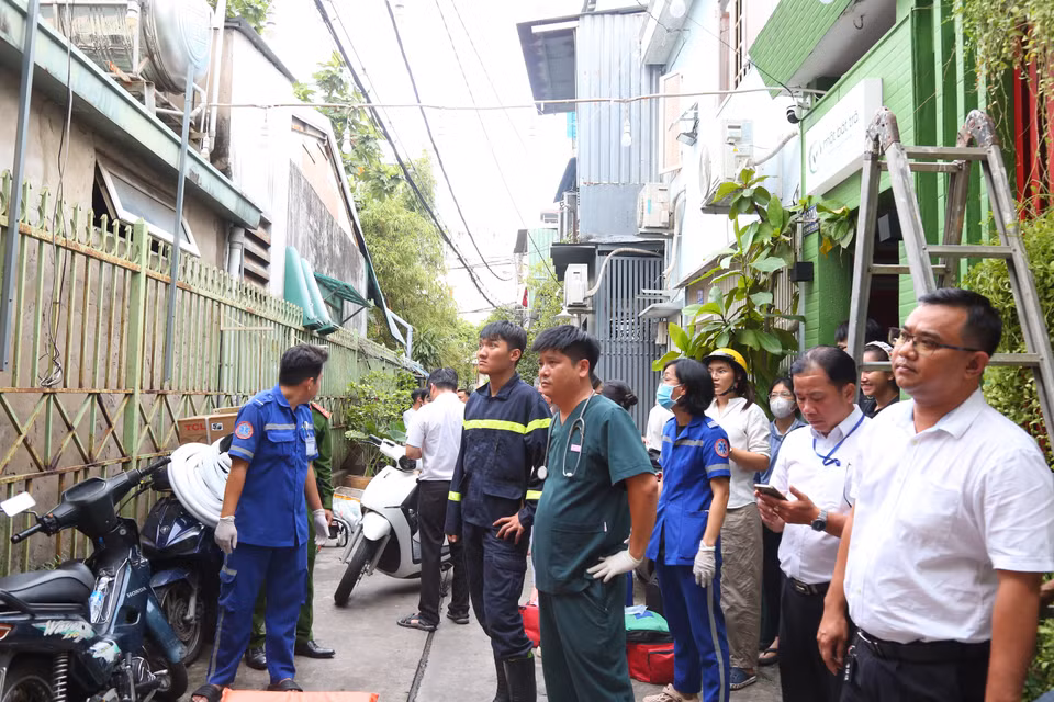 Người dân đứng theo dõi lực lượng chức năng làm nhiệm vụ giải cứu người mắc kẹt. (Ảnh: PV/Vietnam+)