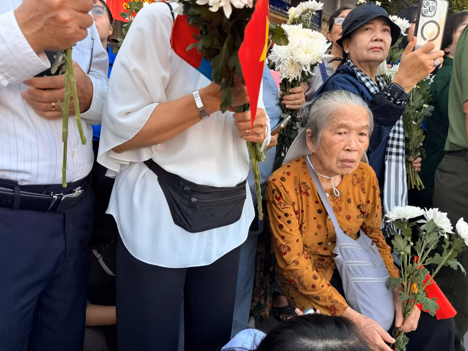 Cụ bà ngồi buồn, tiễn biệt đồng đội. (Ảnh: PV/Vietnam+)