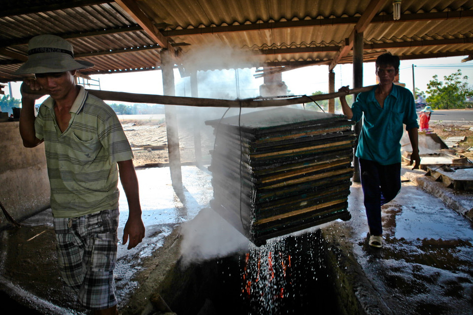 Cá cơm đánh bắt về được ngâm nước muối cho hết nhớt, sau đó được rửa sạch và cho vào lò hấp chừng 5-10 phút trước khi đem phơi. (Ảnh: Trọng Đạt/TTXVN)