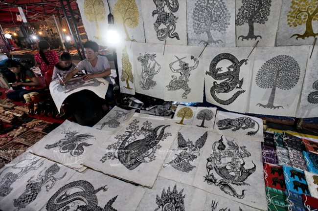 Một gian hàng của người vẽ tranh trên giấy saa truyền thống ở chợ đêm Luang Prabang.