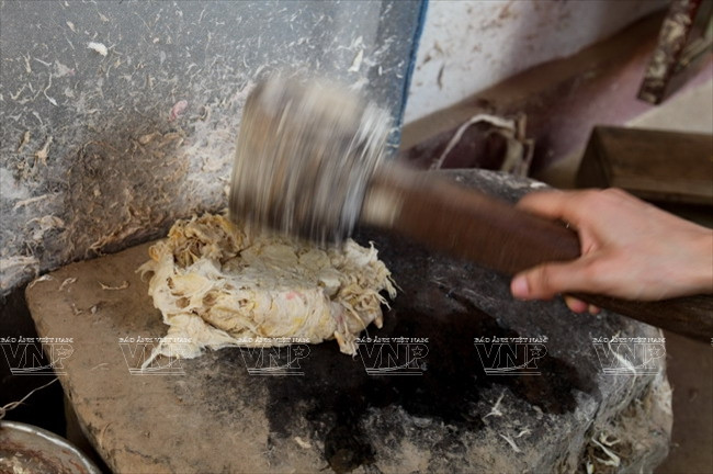 Người dân Lào dùng chày cối đá để đập vỏ cây dâu tằm làm thành nguyên liệu sản xuất giấy.