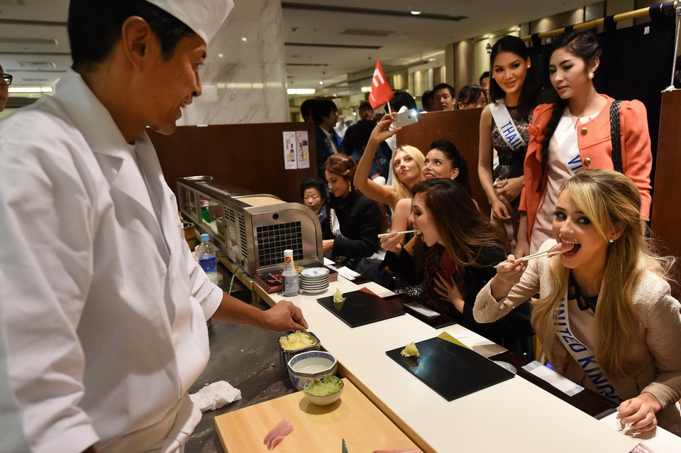 Hoa hậu Việt Nam Đặng Thu Thảo (hàng thứ hai - thứ nhất từ phải) cùng Hoa hậu các nước tại một cửa hàng bánh sushi (bánh nếp Nhật) ở thủ đô Tokyo ngày 1/11. (Ảnh: AFP/TTXVN)
