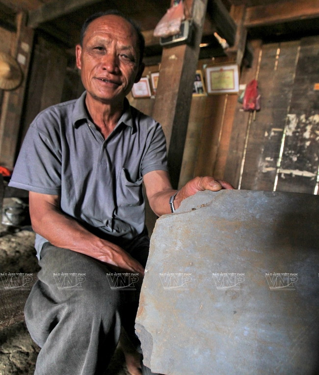 Ông Thào A Mang bên phiến đá được sử dụng để lợp mái nhà. (Nguồn: Báo ảnh Việt Nam)