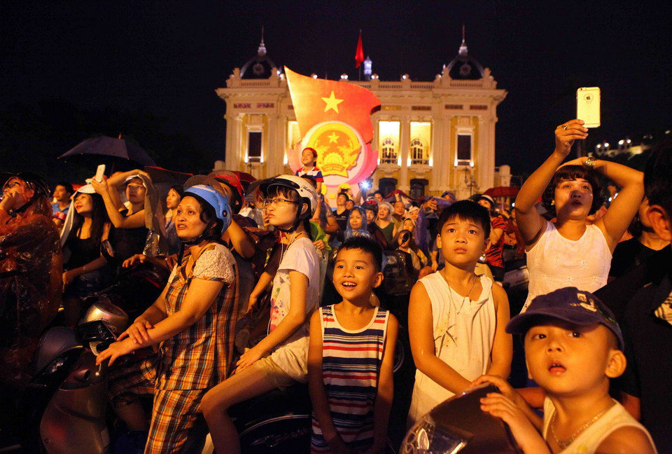 Người dân đứng tại Quảng trường Cánh mạng Tháng Tám xem bắn pháo hoa khu vực Hồ Hoàn Kiếm (Hà Nội). (Ảnh: Quý Trung/TTXVN)