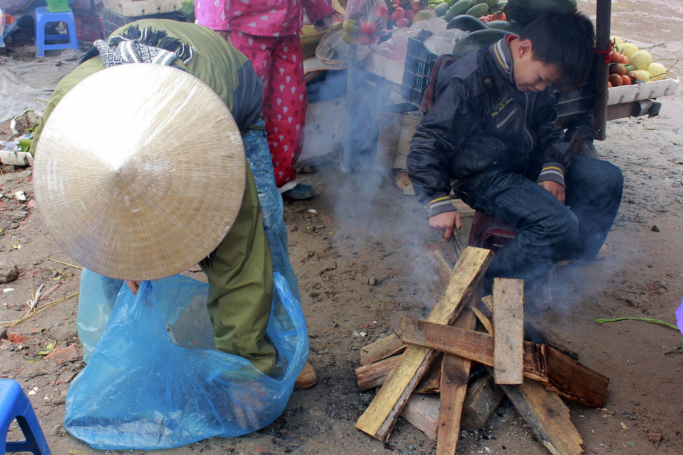 Những người bán hàng phải đốt lửa để sưởi ấm khi nhiệt độ ngoài trời xuống thấp. (Ảnh: Phạm Thảo/TTXVN) 