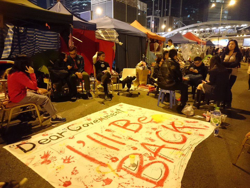 Nhiều khẩu hiệu “Chúng tôi sẽ trở lại” xuất hiện ở khu vực chiếm lĩnh tại Admiralty, Hong Kong (Trung Quốc) trong đêm 10/12 trước khi hoạt động giải tỏa đường phố bắt đầu vào sáng hôm sau. (Ảnh: Hà Ngọc)