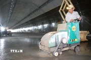 Công nhân thi công hạng mục tạo độ nhám cho mặt đường bên trong hầm. (Ảnh: Hữu Quyết/TTXVN)