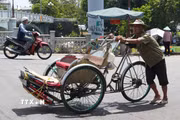 Nhọc nhằn đẩy xe xích lô lên dốc giữa nắng nóng gay gắt ở gần cầu Gia Hội, phường Phú Xuân, thành phố Huế. (Ảnh: Nguyên Lý/TTXVN)