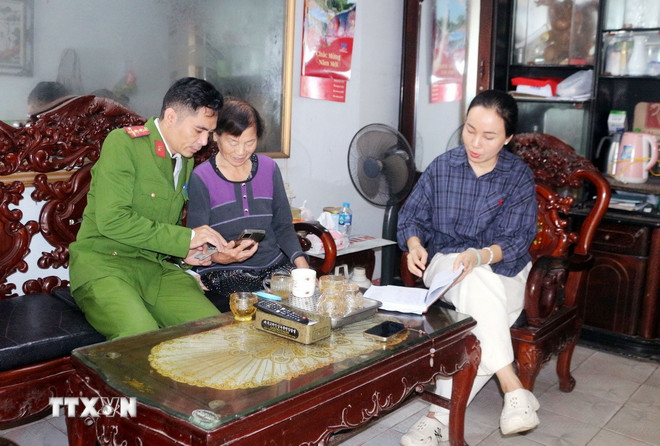 Полиция округа Фули провинции Ниньбинь посетила каждый дом, чтобы разъяснить людям, как принять участие в выражении своего мнения по проектам документов 14-го съезда Национальной партии, используя приложение VNeID. (Фото: Нгуен Чинь/VNA) ttxvn-gop-y-van-kien-dai-hoi-dang-2.jpg