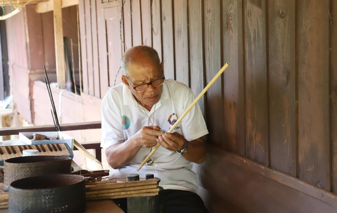លោក Buavanh Oudomsuk កំពុងឆ្លាក់រន្ធនៅក្នុង panpipe ។ (រូបថត៖ Xuan Tu/VNA) thoi-khen-lao-2.jpg