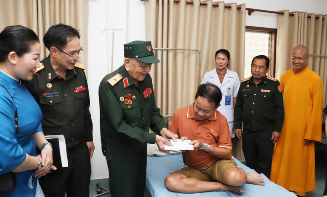 Thiếu tướng Võ Văn Chót, Trưởng ban danh dự Ban Liên lạc quân tình nguyện và chuyên gia quân sự Việt Nam giúp cách mạng Lào tỉnh Nghệ An, trao quà cho thương binh nặng đang điều trị tại Bệnh viện Trung ương Quân đội 103 Lào. (Ảnh: Xuân Tú/TTXVN) tang-qua-quan-nhan-lao-2.jpg