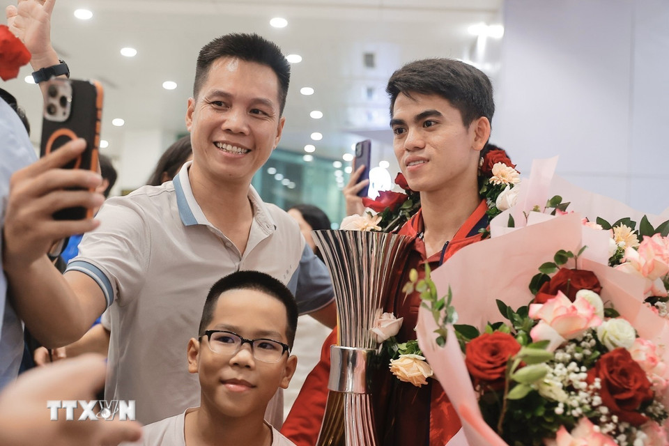 Đội trưởng Khuất Văn Khang chụp ảnh cùng người hâm mộ. (Ảnh: Minh Quyết/TTXVN)