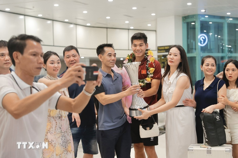 Trung vệ Hiểu Minh bên người thân và người hâm mộ tại sân bay Nội Bài. (Ảnh: Minh Quyết/TTXVN)