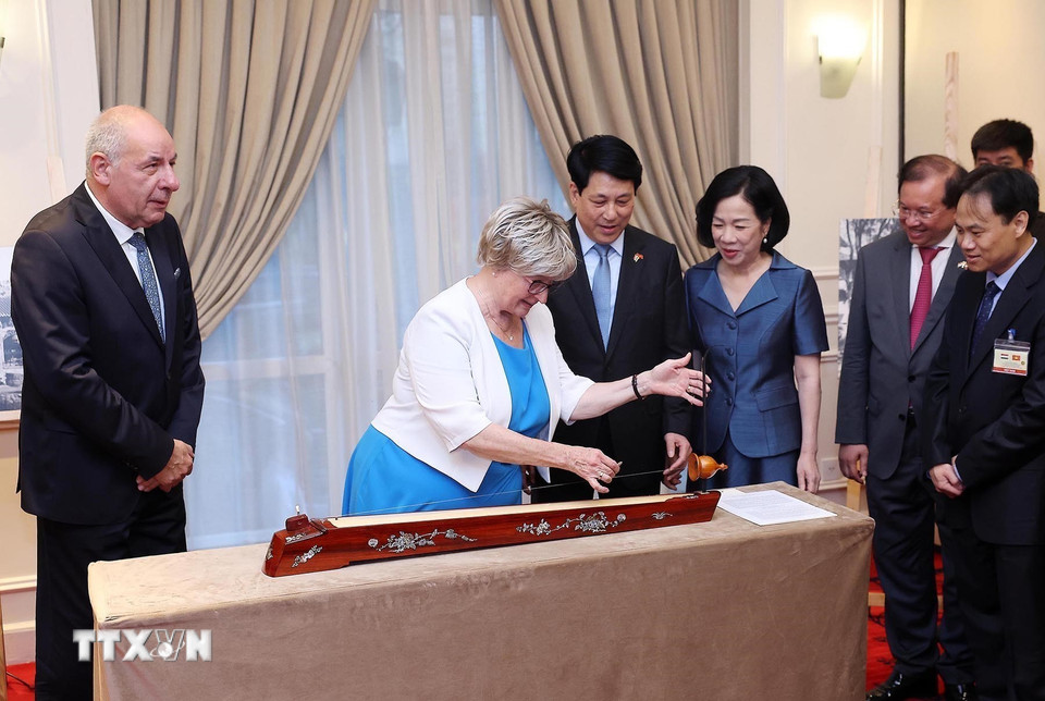 Tại lễ khai mạc trưng bày ảnh, Chủ tịch nước Lương Cường và Phu nhân chứng kiến Phu nhân Tổng thống Hungary Sulyok Tamas trải nghiệm đánh đàn bầu của Việt Nam. (Ảnh: Lâm Khánh/TTXVN)