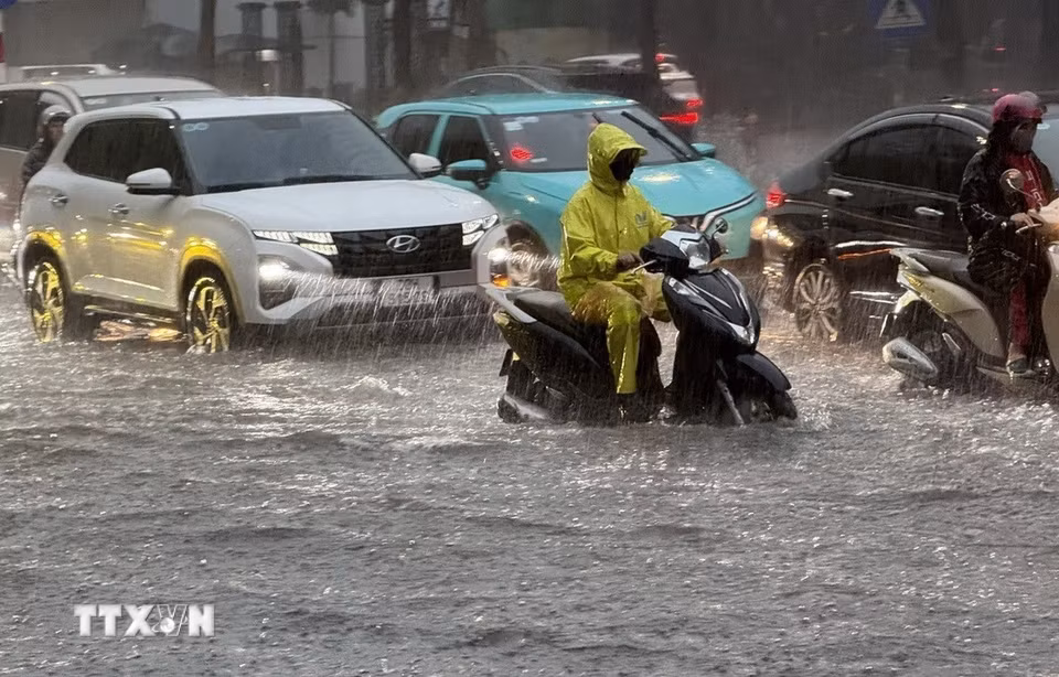 Mưa lớn gây ngập úng cục bộ tuyến phố Nguyễn Văn Cừ, Long Biên khiến các phương tiện tham gia giao thông khó khăn. (Ảnh: An Đăng/TTXVN)