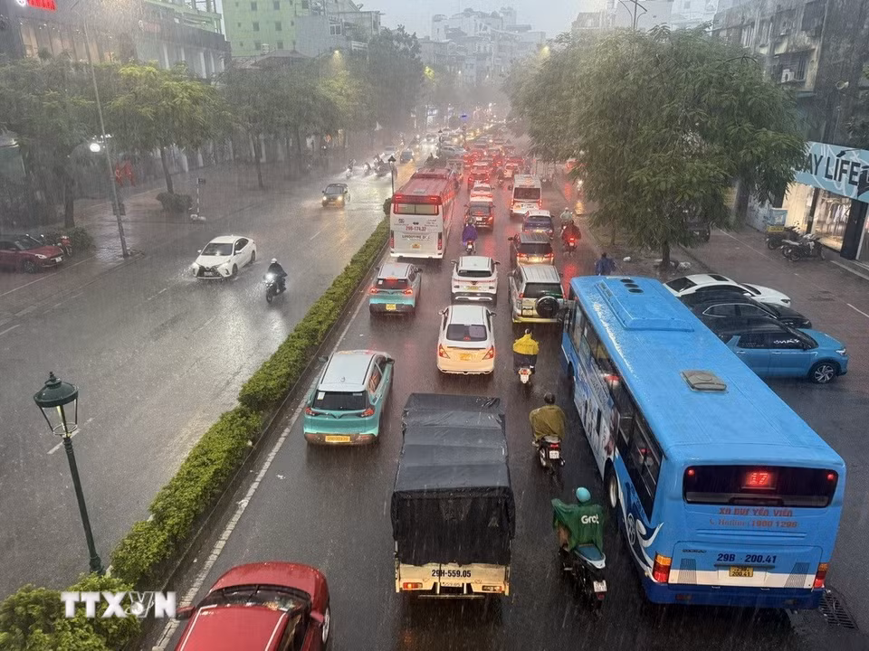 Các phương tiện tham gia giao thông trên tuyến phố Nguyễn Văn Cừ, Long Biên di chuyển khó khăn do mưa lớn gây ngập úng cục bộ. (Ảnh: An Đăng/TTXVN)