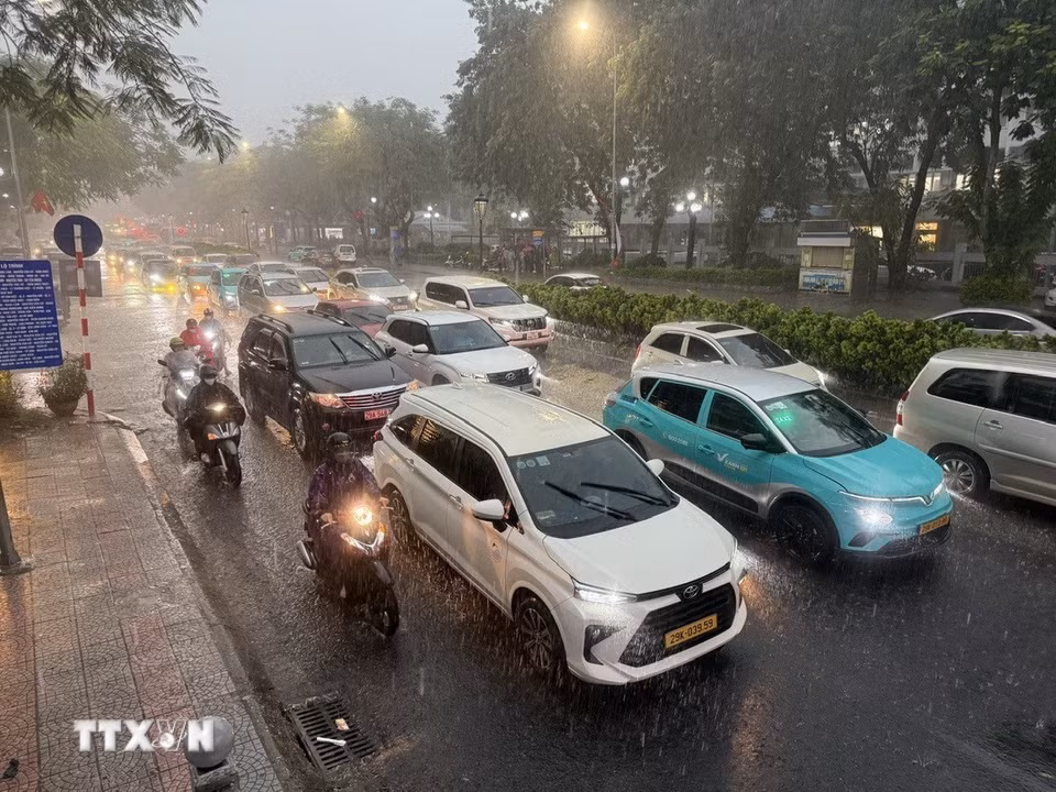 Các phương tiện tham gia giao thông trên tuyến phố Nguyễn Văn Cừ, Long Biên di chuyển khó khăn do mưa lớn gây ngập úng cục bộ. (Ảnh: An Đăng/TTXVN)