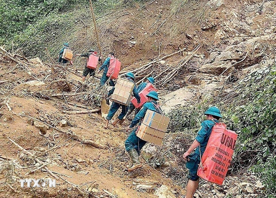 Các lực lượng cõng nhu yếu phẩm cần thiết vượt núi, băng rừng, lội suối vào tiếp tế cho các hộ xã biên giới Yên Nhân (Thanh Hóa) bị sạt lở cô lập. (Nguồn: TTXVN phát)