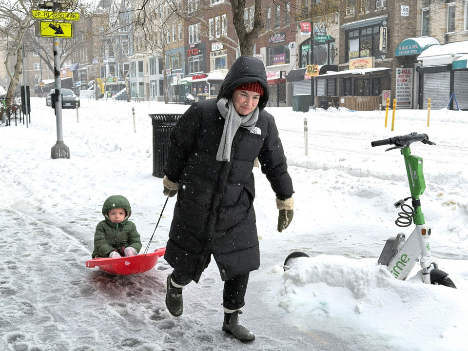 Một phụ nữ kéo con trên ván trượt tại một tuyến phố ở Washington DC ngày 25/1/2026. (Ảnh: Ngọc Quang/TTXVN)