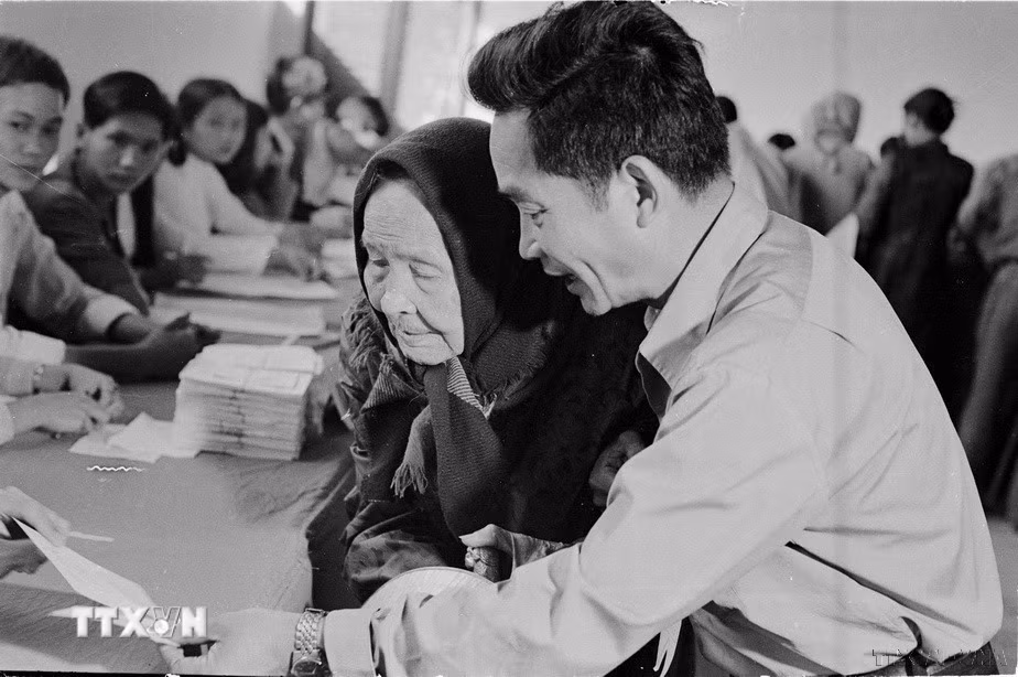 Ngày 25/4/1976, trên 23 triệu cử tri của nước Việt Nam thống nhất đã nô nức đi bầu cử. Đây thực sự là ngày hội lớn của toàn dân Việt Nam. Trong ảnh: Cụ Lê Thị Dưỡng (86 tuổi, Huế), già yếu vẫn nhờ người cõng đến hòm phiếu tham gia bầu cử đại biểu Quốc hội thống nhất (25/4/1976). (Ảnh: Sỹ Thái/TTXVN)