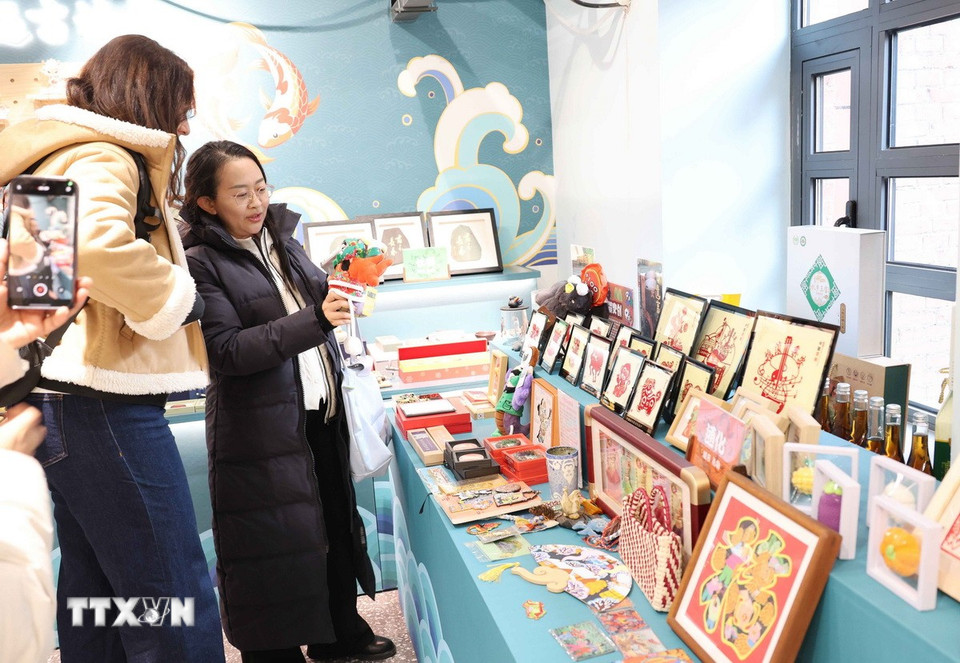 Du khách tìm hiểu về nghệ thuật chế tác tranh da cá ở tỉnh Cát Lâm. (Ảnh: Công Tuyên/TTXVN)