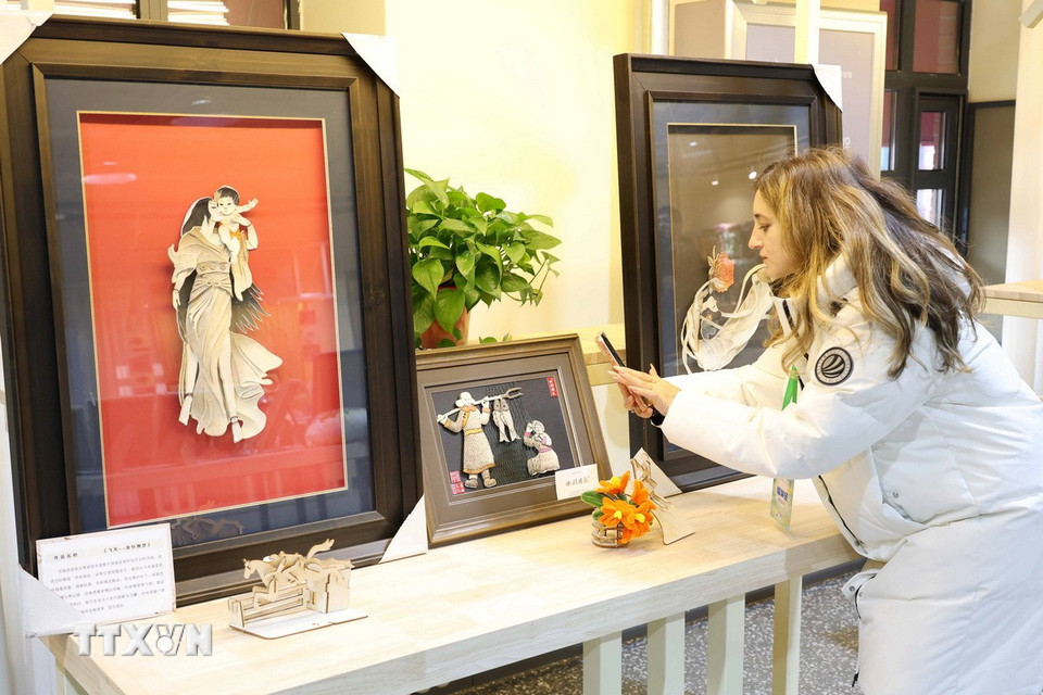 Du khách tìm hiểu về nghệ thuật chế tác tranh da cá của tỉnh Cát Lâm. (Ảnh: Công Tuyên/TTXVN)