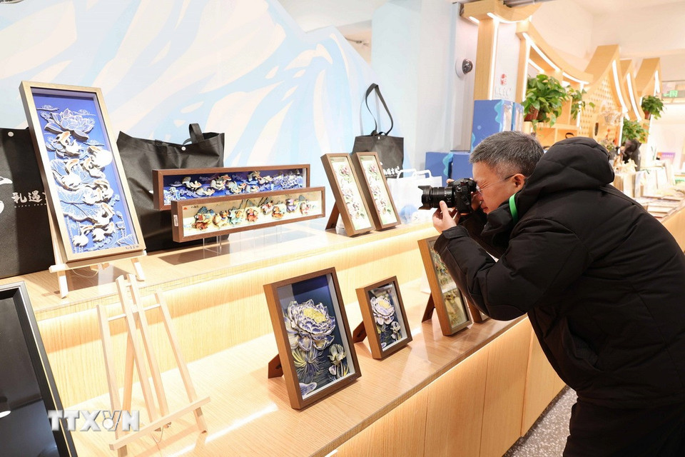 Du khách tìm hiểu về nghệ thuật chế tác tranh da cá của tỉnh Cát Lâm. (Ảnh: Công Tuyên/TTXVN)