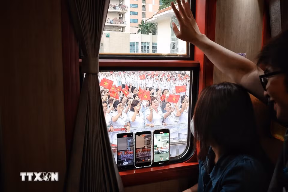 Qua ô cửa đoàn tàu, các cán bộ, nhân viên Bet88013 com nổ hũ Bệnh viện Bạch Mai vẫy chào đồng nghiệp trên chuyến tàu chuyên dụng Hà Nội-Phủ Lý trong ngày đầu vận hành. (Ảnh: Phạm Tuấn Anh/TTXVN)