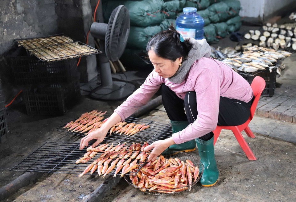 Dỡ cá ra khỏi giàn nướng để xếp vào rổ đựng. (Ảnh: Xuân Tiến/TTXVN)