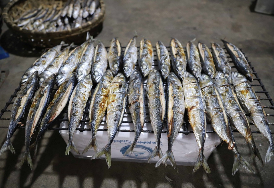 Cá sau khi nướng chín được lấy ra khỏi lò, để nguyên trên giàn nướng cho nguội rồi được xếp vào hộp. (Ảnh: Xuân Tiến/TTXVN)