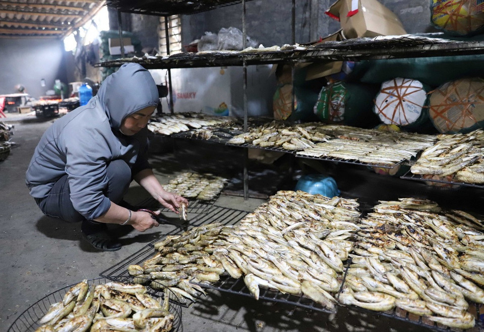 Làm sạch cá sau khi đã nướng chín để xếp vào rổ đựng. (Ảnh: Xuân Tiến/TTXVN)