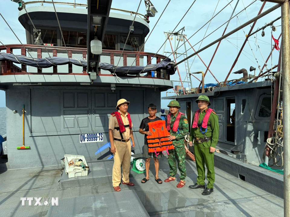 Chiến sỹ Bộ đội Biên phòng đồn Trà Cổ (Bộ đội Biên phòng Quảng Ninh) phối hợp tặng áo phao cho ngư dân. (Ảnh: Thanh Vân/TTXVN)