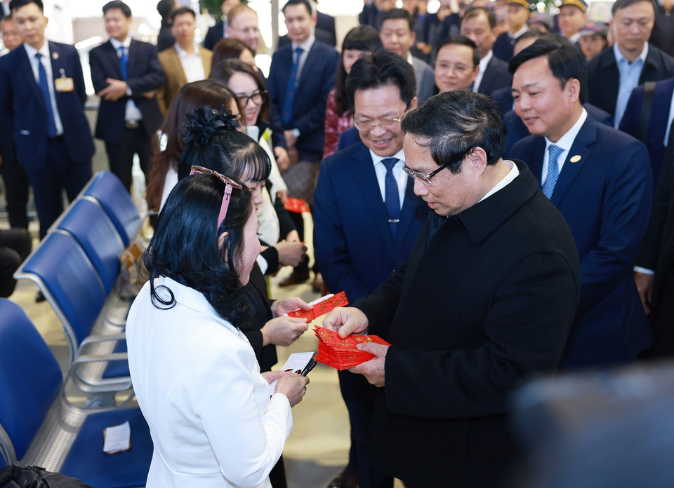 Thủ tướng Phạm Minh Chính chúc Tết, tặng lì xì cho hành khách tại ga tàu Hà Nội. (Ảnh: Dương Giang/TTXVN)