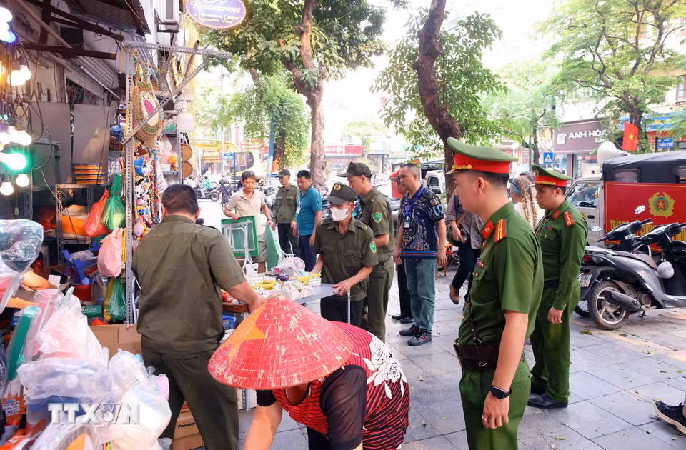 Tổ công tác của Công an phường Hoàn Kiếm xử lý vi phạm về trật tự đô thị tại phố Trần Phú. (Ảnh: Phạm Kiên/TTXVN)