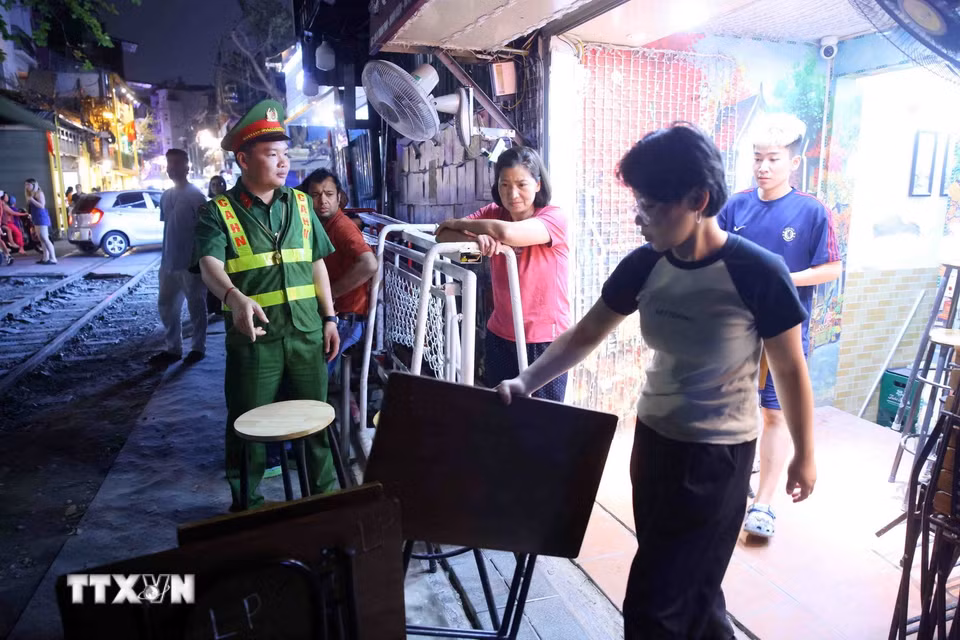 Tại khu vực "cà phê đường tàu", nhiều cơ sở kinh doanh đồ uống tự ý kê bàn ghế sát đường ray, thu hút du khách chụp ảnh, tiềm ẩn nguy cơ mất an toàn. Công tác xử lý được triển khai nhanh chóng nhằm bảo đảm an toàn cho các chuyến tàu qua khu vực. (Ảnh: Phạm Kiên/TTXVN)
