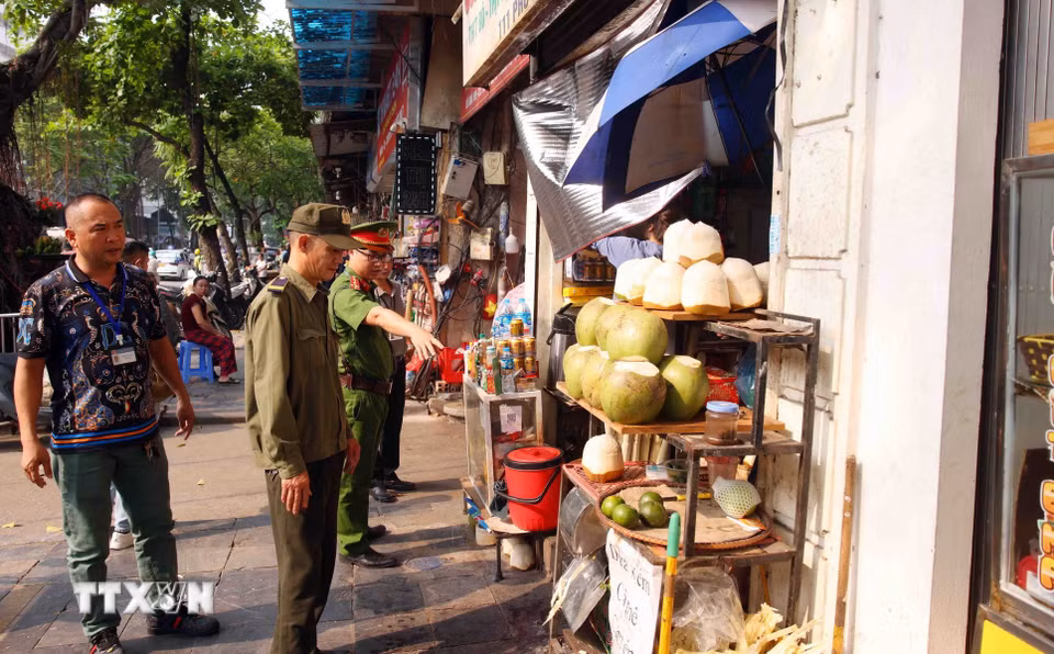 Tổ công tác của Công an phường Hoàn Kiếm xử lý vi phạm về trật tự đô thị tại phố Phủ Doãn. (Ảnh: Phạm Kiên/TTXVN)
