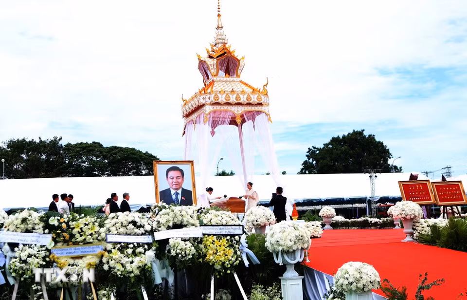 Gia quyến đồng chí Xaysomphone Phomvihane thực hiện nghi thức tưới nước cầu siêu thoát. (Ảnh: Xuân Tú/TTXVN)