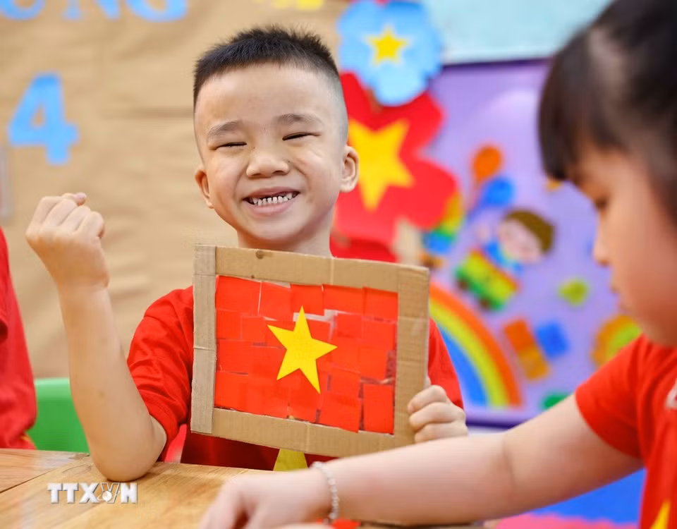 Trẻ thật vui và tự hào khi hoàn thành sản phẩm là lá cờ Tổ quốc của mình. (Ảnh: Thanh Tùng/TTXVN)