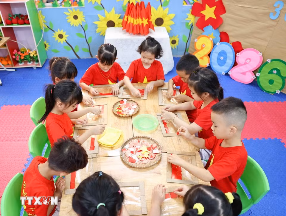 Chỉ bằng những nguyên vật liệu đơn giản, với keo dán trẻ đã tạo ra lá cờ Tổ quốc xinh xắn. (Ảnh: Thanh Tùng/TTXVN)