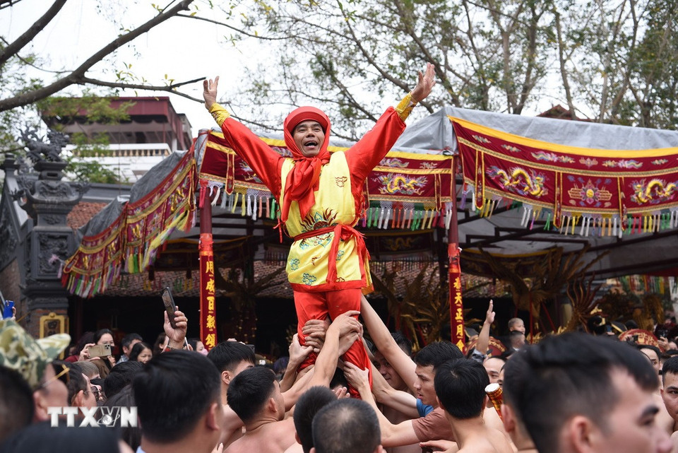 Các thanh niên tuổi từ 18 trở lên ở các dòng họ trong phường Đồng Kỵ tham gia đỡ 4 ông quan đám biểu diễn ở sân đình. (Ảnh: Thanh Thương/TTXVN)