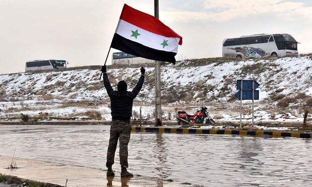 Một người vẫy cao lá cờ Syria sau khi chiến binh nổi dậy cuối cùng rời khỏi Aleppo (Nguồn: Guardian) Người dân Aleppo đổ ra đường ăn mừng thành phố được giải phóng ảnh 1