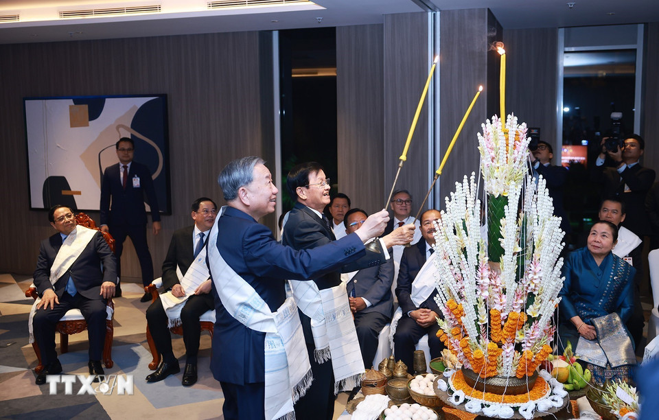 Tổng Bí thư Tô Lâm cùng Tổng Bí thư, Chủ tịch nước Lào Thongloun Sisoulith thực hiện nghi lễ buộc chỉ cổ tay truyền thống của Lào. (Ảnh: Dương Giang/TTXVN)