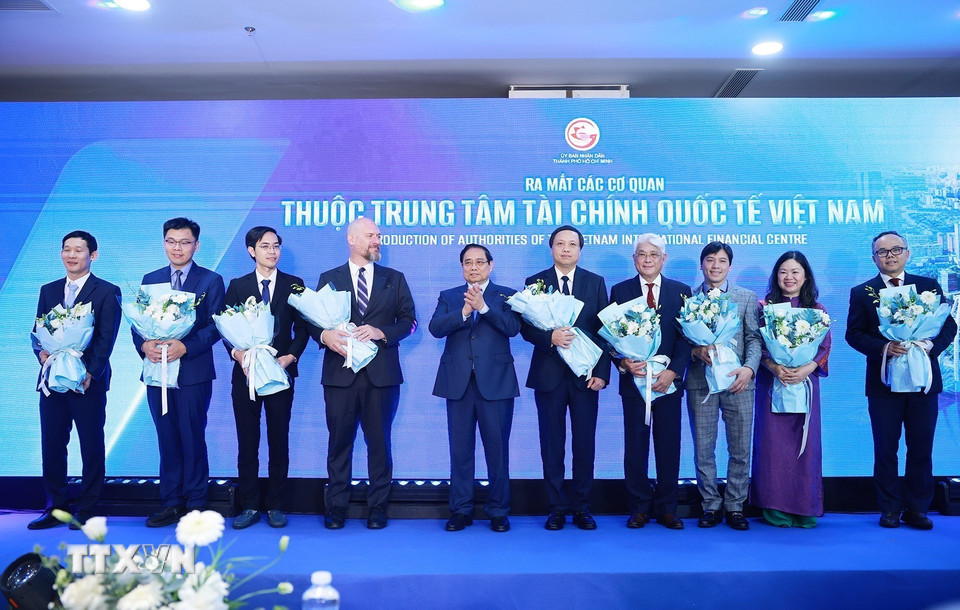 Thủ tướng Phạm Minh Chính tặng hoa cho đại diện các cơ quan thuộc Trung tâm Tài chính quốc tế Việt Nam. (Ảnh: Dương Giang/TTXVN)