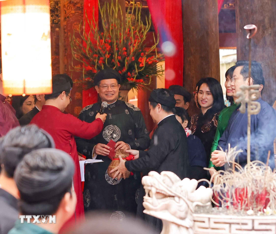 Đại biểu dự lễ viết câu nguyện ước năm mới vào giấy rồi bỏ vào giỏ để treo lên cây nêu. (Ảnh: Thanh Tùng/TTXVN)