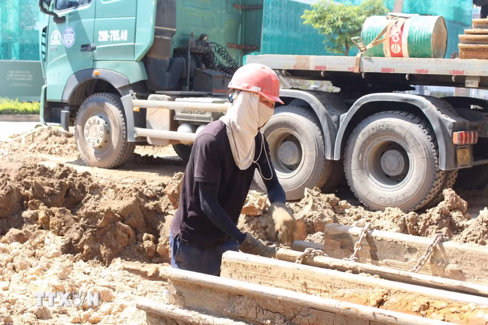 Công nhân căng mình làm việc trong điều kiện thời tiết nắng nóng gay gắt để đảm bảo tiến độ dự án. (Ảnh: Nguyễn Thắng/TTXVN)