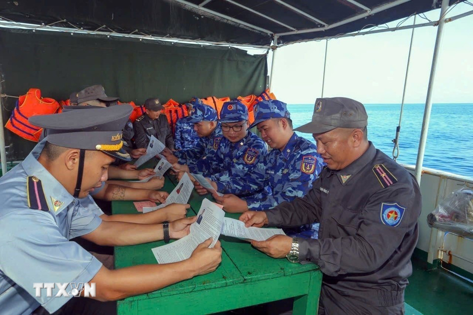 Cử tri trên tàu trực tìm hiểu thông tin về ứng cử viên. (Ảnh: TTXVN phát)