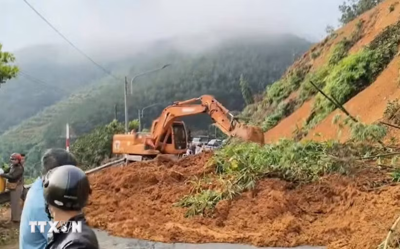 Máy xúc khẩn trương thu dọn đất tràn xuống mặt đường tỉnh 755B, đoạn qua xã Phước Sơn, thành phố Đồng Nai, sau mưa lớn kéo dài. (Ảnh: TTXVN phát)